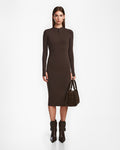 A woman stands facing forward in the Rudsak AGNES - 8524551 Espresso fitted, long-sleeve bodycon dress against a plain white background, styled with matching dark brown boots and handbag.