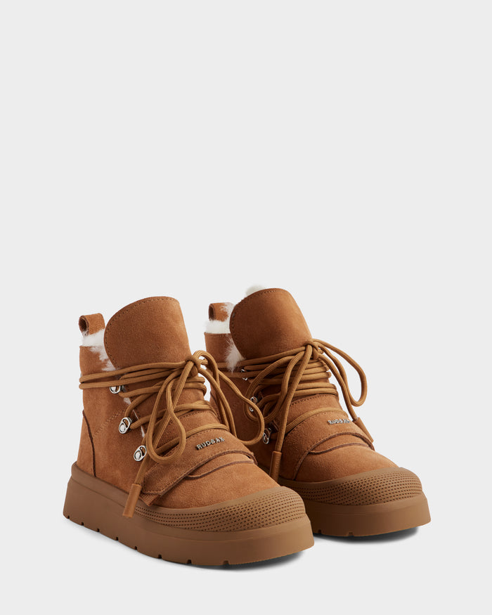 The ALEXEY - L225025 Tan by Rudsak are brown women’s suede winter boots with thick rubber soles, metal eyelets, tan laces, and a plush wool lining at the top for warmth and comfort.