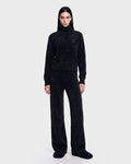 A person stands facing forward, wearing the Rudsak ALISYA - 8526505 Black fuzzy turtleneck sweater with matching wide-leg pants and slippers. The background is plain and light-colored.