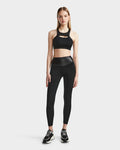 A woman faces forward wearing the ARYA - 8523002 BLACK crop top and matching high-waisted leggings by RUDSAK, paired with black sneakers, set against a plain light background.