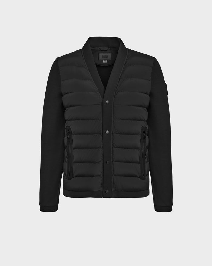 The Rudsak ATOM - 6124591 Black is a mens hybrid jacket with long sleeves, a quilted padded front, button closure, zippered side pockets, and ribbed cuffs—perfect for transitional weather. Shown on a plain light gray background.