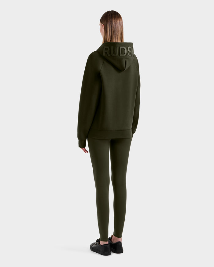 A person faces away, wearing the Rudsak BARRY - 9524011 hoodie in dark olive, paired with matching leggings and black sneakers, set against a plain light background.