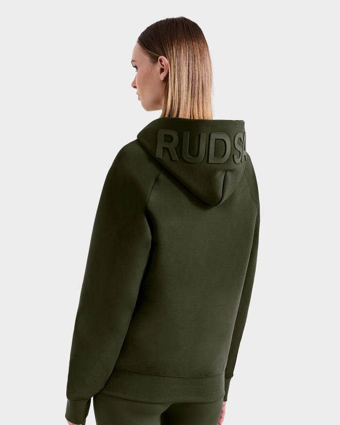 A person with straight, shoulder-length hair, facing away from the camera, is wearing a Rudsak BARRY - 9524011 Dark Olive W oversized hoodie with "RUD" in raised letters on the hood, set against a plain light background.