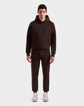 A man stands facing forward against a white background, wearing the Rudsak BARRY - 9524011 Espresso M hoodie and matching jogger pants, paired with light-colored sneakers.