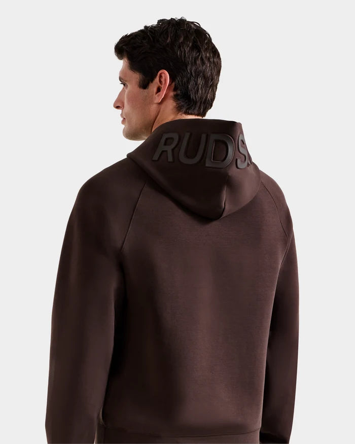 A man with short brown hair is seen from behind, wearing the Rudsak BARRY - 9524011 Espresso M unisex hoodie featuring raised branding on the hood. The background is plain white.