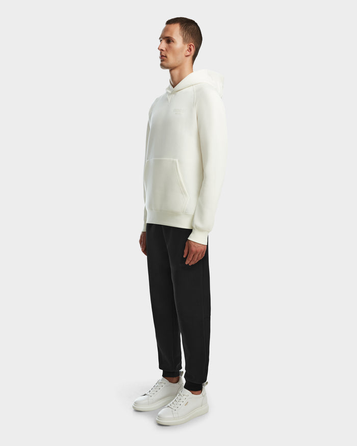 A man stands facing slightly left, wearing the Rudsak BARRY - 9524011 Iceland M oversized hoodie, black pants, and white sneakers against a plain light gray background.