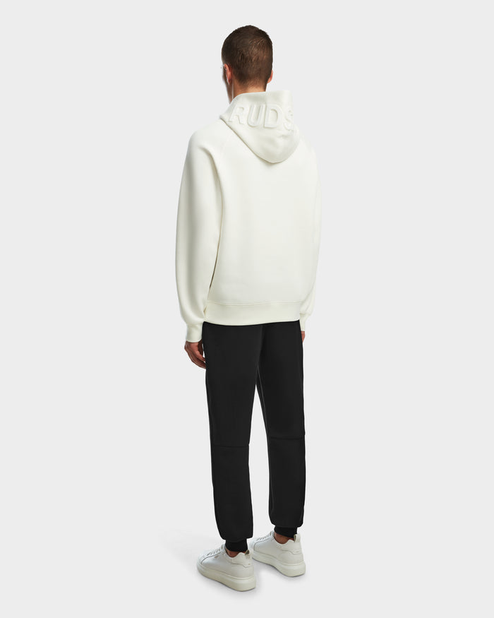 A person faces away, wearing the Rudsak BARRY - 9524011 Iceland M oversized white hoodie with embossed hood text, black pants, and white sneakers against a plain light background.