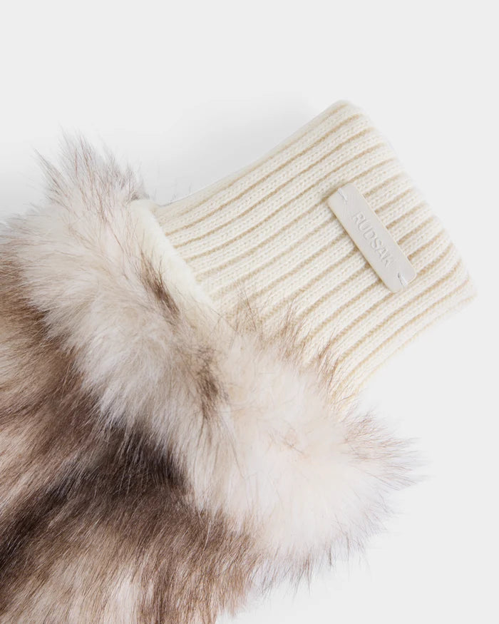 A cream-colored ribbed cuff featuring a white label marked “Rudsak” is attached to the fluffy brown-and-white faux fur sleeve of the BELLA - 8425006 Mix Vanilla mitten, making it a stylish winter accessory, all set against a white background.