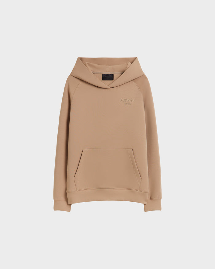 The BRIAR - 9525001 Almond M by Rudsak is a tan unisex hoodie made from a premium cotton blend, featuring long sleeves, a front kangaroo pocket, and a subtly embroidered RUDSAK logo on the chest against a white background.