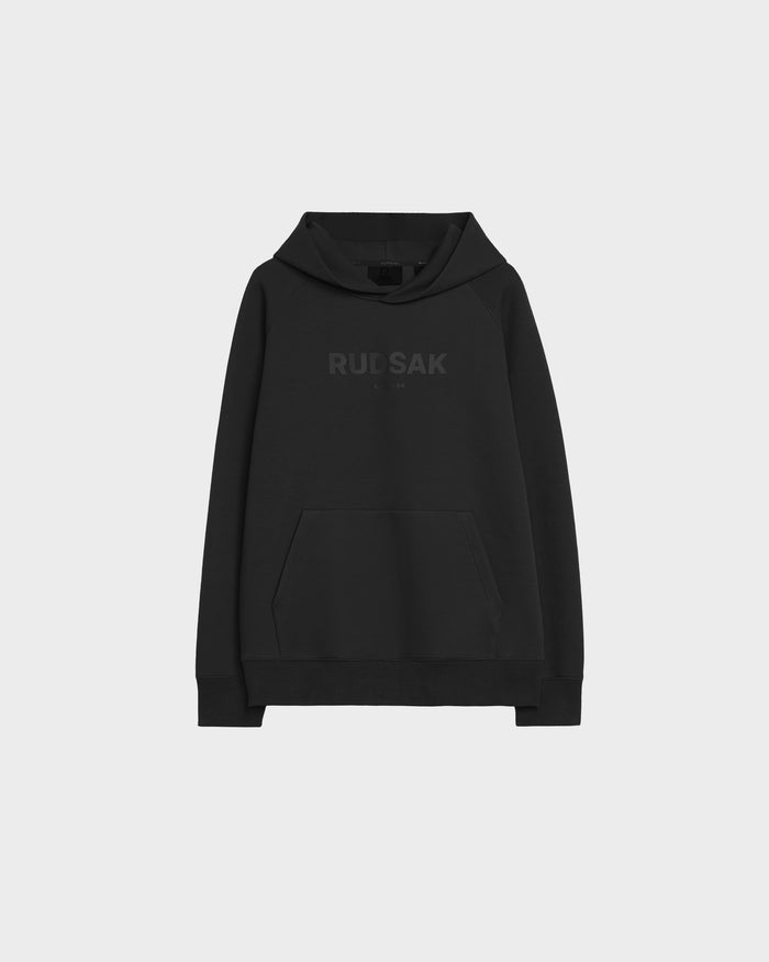 The Rudsak BRIAR - 9525001 Black M is a unisex cotton-blend hoodie with a front pocket and subtle black RUDSAK text across the chest, shown on a plain light grey background.