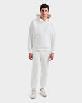 A man faces forward in a Rudsak BRIAR - 9525001 Iceland M unisex hoodie with premium cotton blend, front pocket, and matching white jogger pants. He pairs them with light sneakers against a simple, light-colored background.