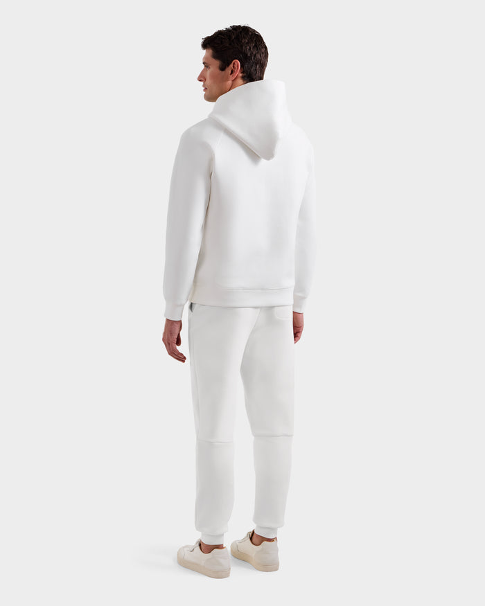 A man in the Rudsak BRIAR - 9525001 Iceland M unisex hoodie, white sweatpants, and white sneakers stands facing away, glancing over his shoulder against a light background for a casual look.