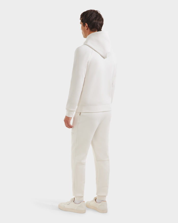 A person stands facing away, wearing the Rudsak BROOKLYN - 6525593 Vanilla hoodie and jogger set, paired with white sneakers against a plain light background.
