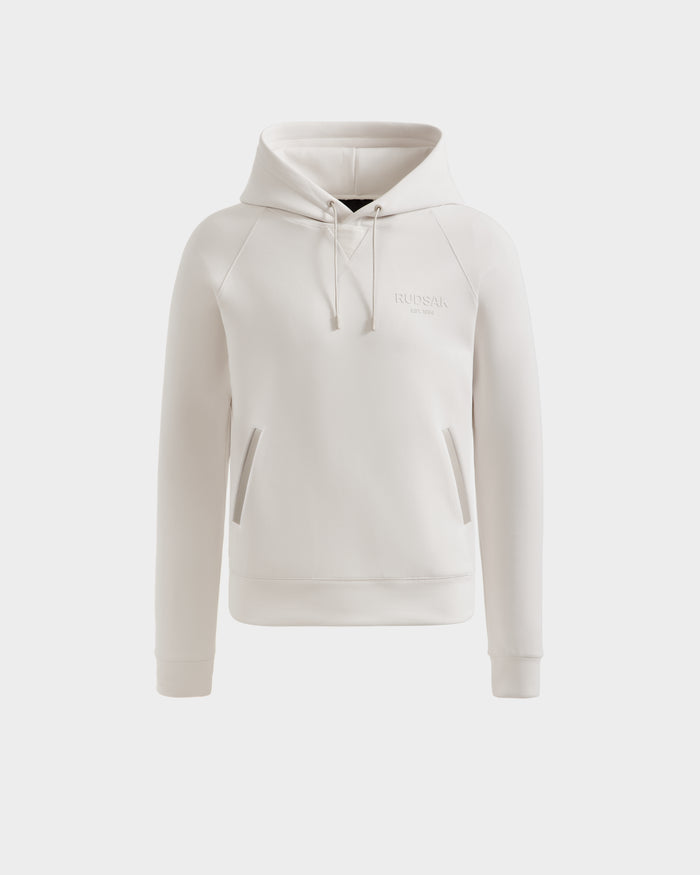 The Rudsak BROOKLYN - 6525593 Vanilla is a light beige cotton-blend hoodie with long sleeves, front pouch pockets, and adjustable drawstrings, shown on a white background.