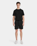 A man faces forward wearing Rudsak’s CAMDEN - 6525028 Black t-shirt and jogger shorts with white sneakers against a plain white background—an ideal look for any casual wardrobe.
