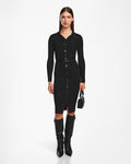 A woman poses against a white background wearing the Rudsak CARLI - 8524573 Black knit dress with a collar, vegan leather belt, knee-high black boots, and holding a small black handbag.