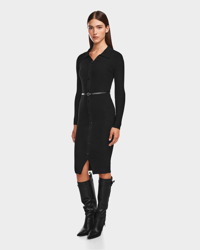 A woman wears the CARLI - 8524573 Black knit dress by Rudsak with a vegan leather belt and knee-high black boots, posing against a plain light background.