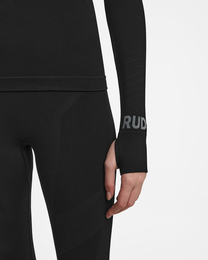 A person wears the Rudsak CARRIE - 8524619 Black sportswear featuring thumbhole sleeves and RUD in gray near the wrist, ideal as a ski base layer. Set against a plain white background.