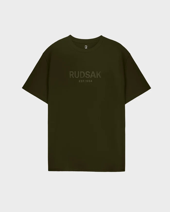 The Rudsak CASEY - 6525037 men’s T-shirt in dark olive features subtle “RUDSAK EST. 1994” embossing across the chest, shown against a light gray background.