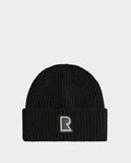The Rudsak CYBELLE - 9424504 Black/Silver beanie is a unisex wool blend hat with ribbed knit, folded brim, and an embroidered R patch on the front, shown against a plain white background.