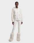 A person stands against a plain light background wearing the Rudsak DAKOTA - 8526515 Iceland cozy white sherpa hoodie, paired with white leggings and fluffy white boots.