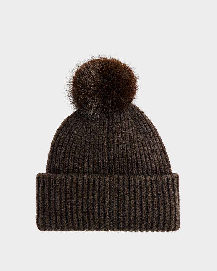 The Rudsak DARA - 8425019 Dark Olive is a ribbed knit beanie with a wide cuff and a plush faux fur pom pom—your must-have for cozy, cold-weather style.