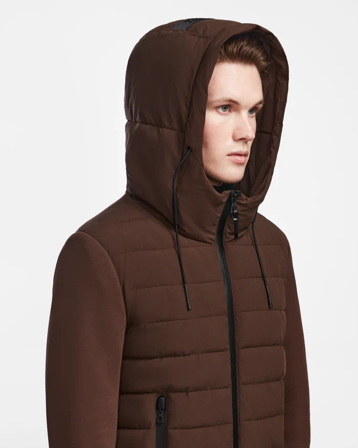 A man wearing the Rudsak ELIAS - M124002 Espresso quilted jacket with black zippers and drawstrings, looking to the side against a plain white background.
