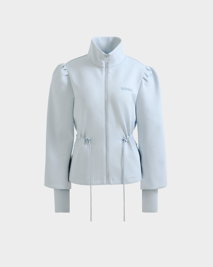 The ELODIE - 8526039 Powder Blue by Rudsak is a light blue zip-up sweater jacket with a high collar, long puffed sleeves, stretch cotton blend, drawstring waist, and subtle chest logo, shown on a plain white background for a sporty-casual vibe.