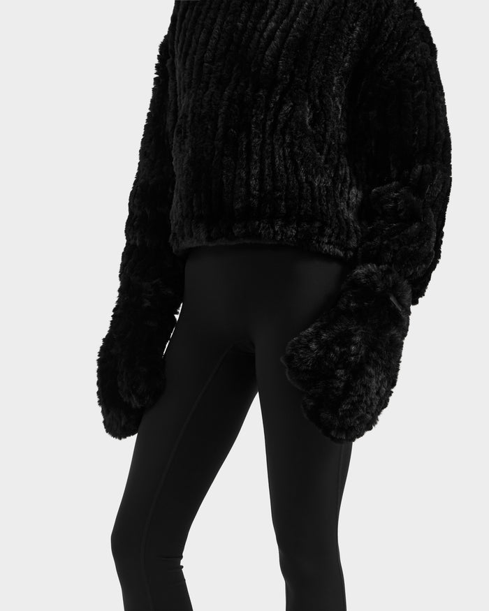 Wearing the Rudsak ELOISE - 8425559 Black oversized textured faux fur sweater with matching women's mittens and black fitted leggings, this look channels après-ski chic against a plain white background. The head and feet are not shown.