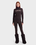 A woman wearing the ERIKA - 8525705 Espresso turtleneck sweater by Rudsak, paired with black leggings and black fur boots, stands against a plain white background, facing forward with a neutral expression—the perfect look to elevate any winter wardrobe.
