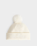 A cream-colored knit beanie, the ESTELLA - 8426521 Vanilla by Rudsak, features a fluffy pom-pom on top and Les Alpes embroidered in white script on the front cuff.