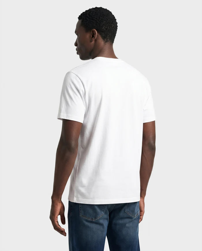 A man, seen from behind, wears the Rudsak FERDI - 6522005 NATURAL WHITE short-sleeve t-shirt with blue jeans against a plain light background.