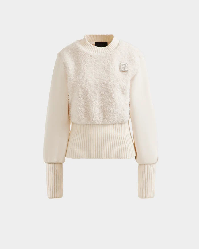 The FLORENCE - 8525546 Iceland by Rudsak is a cream-colored women’s long-sleeve sweater with a fuzzy front, ribbed cuffs and hem, and a decorative R patch—blending cozy glamour with effortless style.