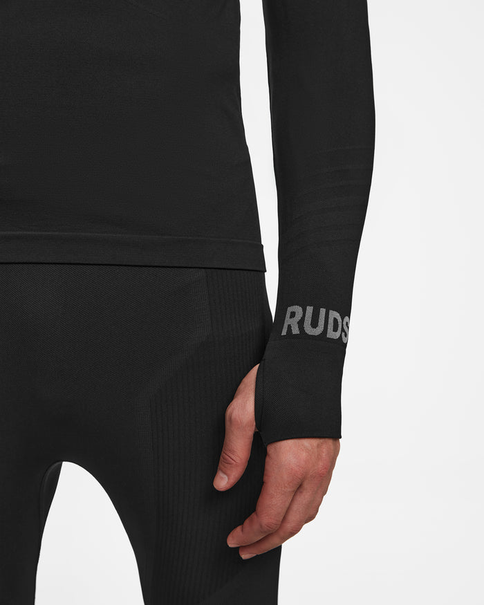 A person wears the FRANC - 6524541 Black fitted long-sleeve top and pants set by Rudsak, with RUDS visible on the sleeve near their relaxed hand. The background is plain white.