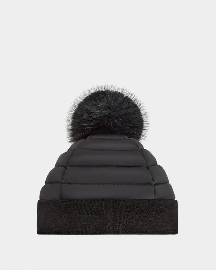 The Rudsak GALA - 8424514 Black is a womens quilted down puffer hat with premium insulation, a wide folded cuff, and a removable faux fur pom-pom, shown in black against a plain white background.