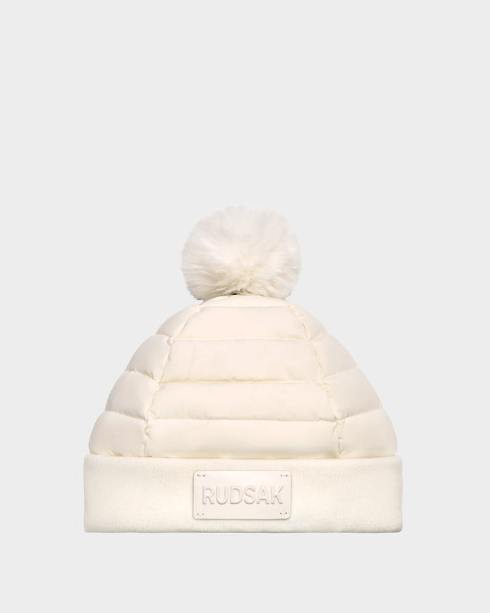 The Rudsak GALA - 8424514 Iceland womens white quilted down puffer hat features premium down insulation, a removable faux fur pom pom, and a folded brim with a Rudsak label, shown against a plain light gray background.