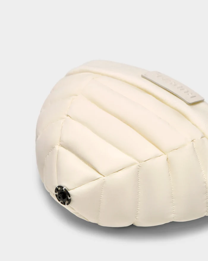 A close-up of the Rudsak GALA - 8424514 Iceland cream quilted bag with premium down insulation, showing a black snap button and a rectangular label on the top right, set against a plain light gray background.