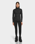 A woman with straight brown hair faces forward, wearing the Rudsak GASIA - 8524567 Black stretch active top and black leggings with chunky black boots against a plain white background.