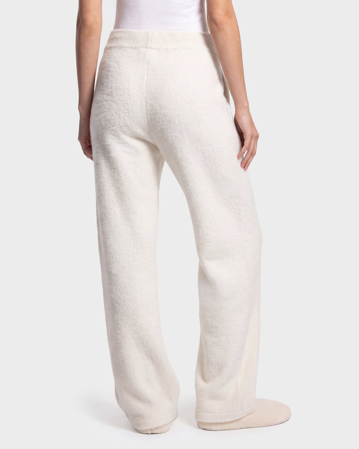 A person shown from the waist down stands against a plain, light-colored background, wearing the Rudsak GENESIS - 8526506 Iceland loose-fitting, textured white pants with matching slippers.