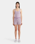 A woman faces forward against a white background wearing Rudsak’s GENEVA - 8524070 Lilac Foam sleeveless bodysuit, double jersey drawstring women’s shorts, and coordinating lavender sneakers.