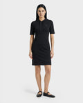 A woman with straight dark hair models the Rudsak GISELA - L524004 Black short-sleeve hooded dress with a front pocket and black flats, standing against a plain white background.