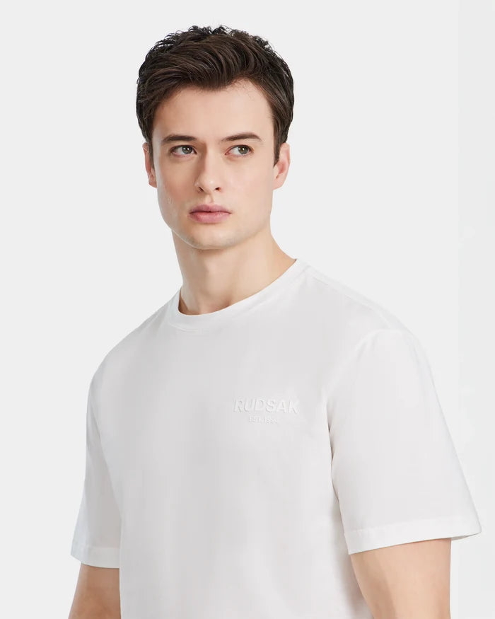 A young man with short brown hair, in a plain white Rudsak GRANT - 6525036 Iceland mens tee, made from premium cotton, gazes slightly left against a simple white background.