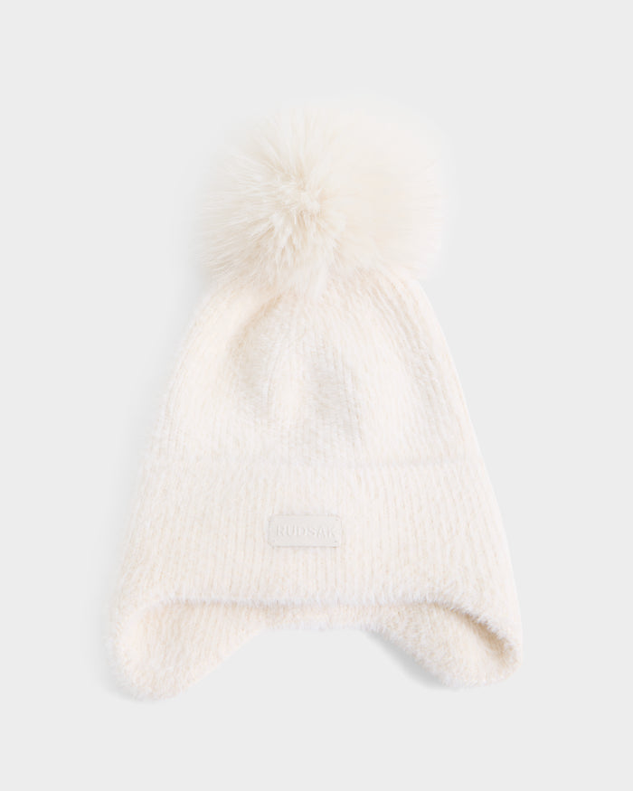 A white knit winter hat from Rudsak, the ICE - 8426519 Vanilla, featuring a large fluffy pom-pom on top, ear flaps, a fold-over cuff, and a small rectangular patch on the front.