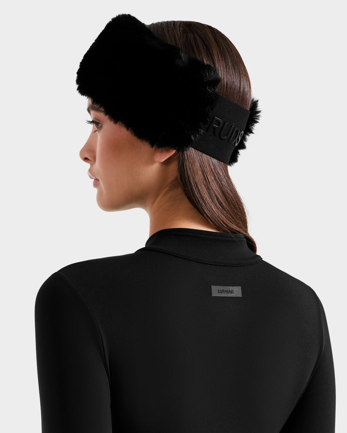 A woman with straight brown hair wears the Rudsak IVY - 8524599 Black stretch bodysuit and a black furry headband, featuring a small rectangular label on the back, shown from behind against a plain light background.