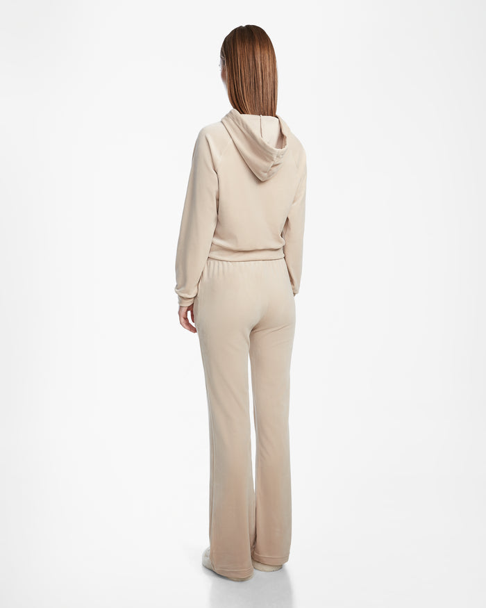 A person with straight, shoulder-length hair is facing away, wearing the Rudsak JODIE - L523501 Cream hooded sweatshirt and velvet pull-on pant with an elastic waistband against a plain white background.