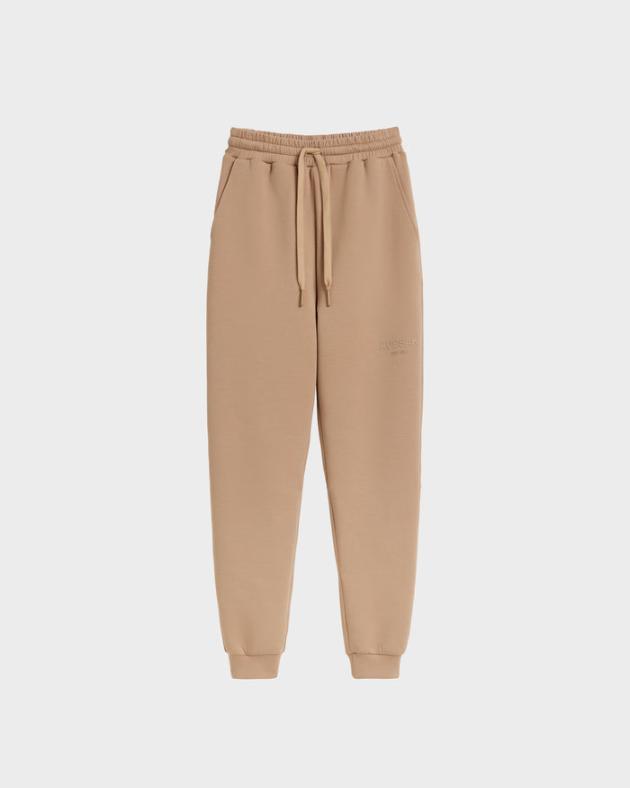 The Rudsak JOSS - 9524009 Almond M joggers showcase premium tan cotton with an elastic waistband, drawstring, side pockets, and ribbed cuffs for stylish comfort, displayed on a plain white background.