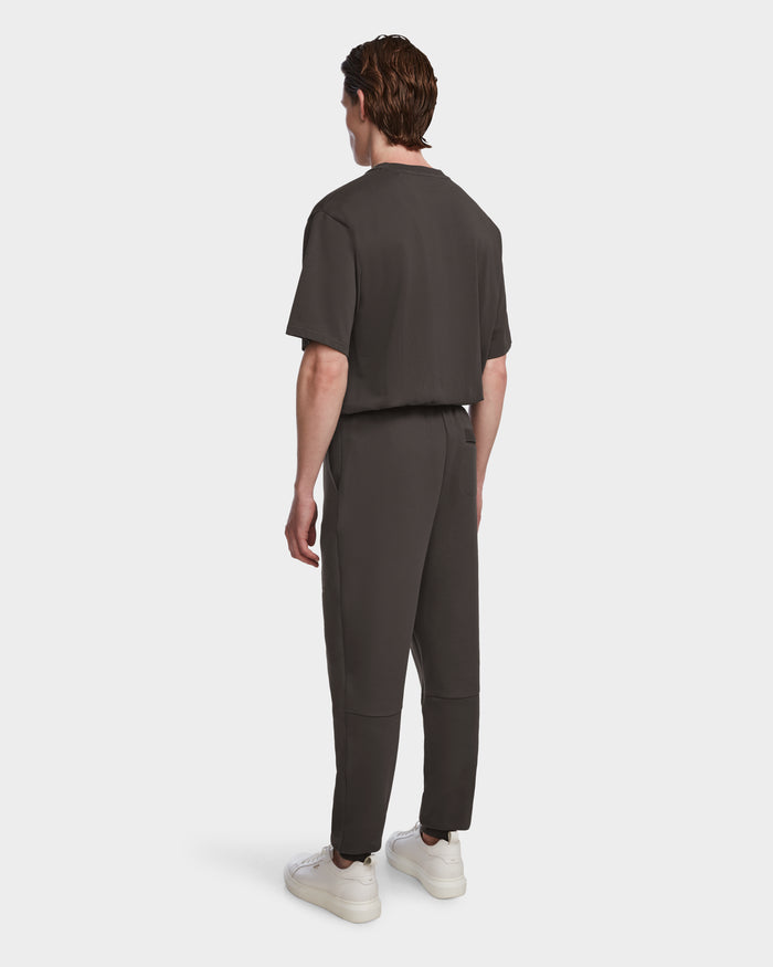 A man with brown hair faces away, modeling the Rudsak JOSS - 9524009 Grey M unisex jogger set and shirt, paired with white sneakers, against a plain white background.