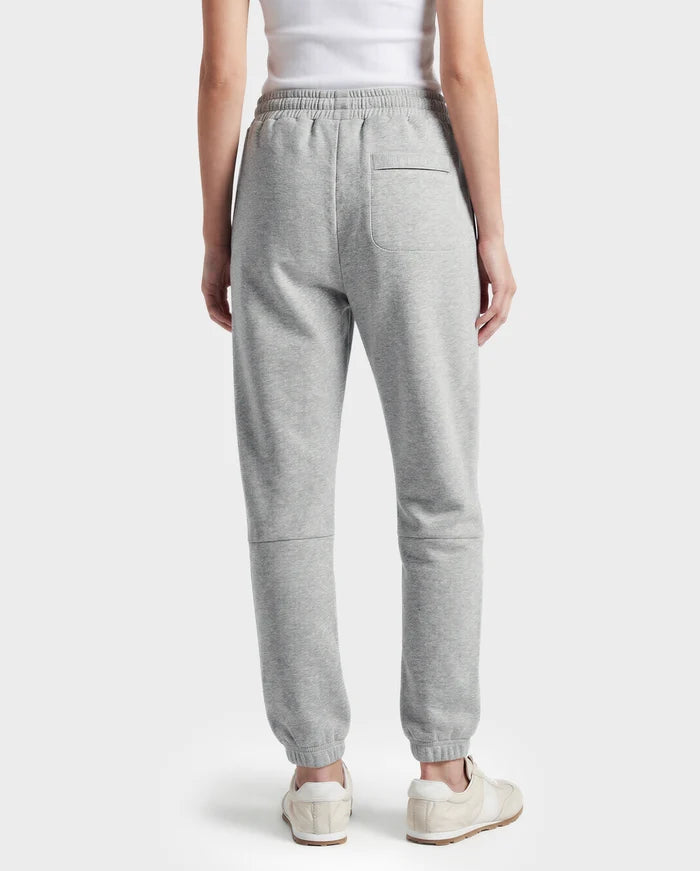 A person stands facing away, wearing a white tank top and Rudsak's JOSS - 9524009 Heather Grey W unisex jogger sweatpants with an elastic waistband and single back pocket, paired with white sneakers for a stylish look.