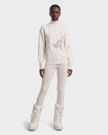 A person stands facing forward against a plain white background, wearing the JOYCE E - 8526538 Vanilla tall, padded boots by Rudsak, paired with an ivory turtleneck sweater and matching fitted pants.