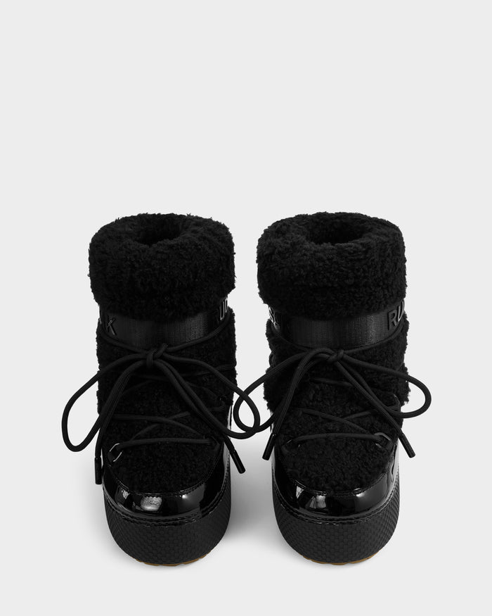 A pair of Rudsak KATHY Y - 1224500 Black water-repellent winter boots with textured fuzzy uppers, shiny black toe caps, thick soles, and black laces, viewed from the front against a plain white background.